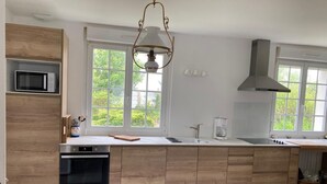 Una cocina moderna con una isla de madera, microondas integrado y un amplio ventanal que proporciona luz natural.