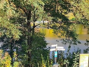 A signpost with directional information near a body of water, surrounded by trees. - Maarchalet Modern Retreat (Daun)