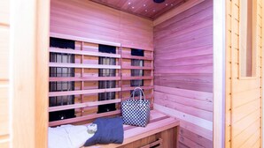 A sauna with wooden benches, shelves with towels, and a checkered bag. - Maarchalet Modern Retreat (Daun)