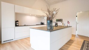 Een moderne keuken met witte kasten, een centraal eiland en een houten vloer.