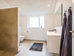 A modern bathroom with a toilet, sink, and shower area. - 5 Star Holiday Home in Blavand (Blavand)