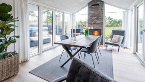 Een ruime kamer met een grote tafel, comfortabele zithoek, een open haard en uitzicht op de omgeving.