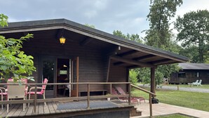 Une cabane en bois dotée d’une véranda, d’un espace extérieur aménagé pour s’asseoir et d’une zone couverte.