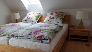 A bedroom with a wooden bed, floral bedding, two bedside lamps, and a skylight.
