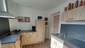 A modern kitchen with wooden cabinets, a built-in microwave, and a stainless steel sink. - Vakantiehuis Mosella (Oberfell)