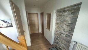 A hallway with wooden flooring, a radiator, and a stone wall. - Vakantiehuis Mosella (Oberfell)