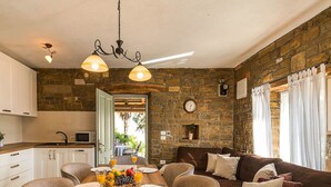 A cozy interior with a stone wall, a dining area with a table set for two, and a comfortable sofa. - Aurora Comfortable Holiday Residence (Oprtalj)