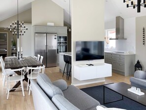 Una sala moderna con comedor, cocina y televisión.