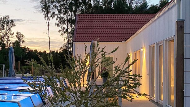 A building with a red-tiled roof, a covered outdoor area with a pool, and a tree in the foreground. - 5 Star Holiday Home in Gotlands Tofta (Gotlands Tofta)