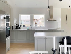 A modern kitchen with grey cabinets, a stainless steel refrigerator, a double sink, and a window with a view of the outside. - 5 Star Holiday Home in Gotlands Tofta (Gotlands Tofta)