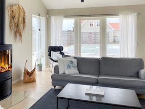 A modern living room with a fireplace, grey sofa, and a coffee table. - 5 Star Holiday Home in Gotlands Tofta (Gotlands Tofta)