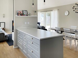 A modern kitchen with a central island, white cabinetry, and a dining area with white chairs. - 5 Star Holiday Home in Gotlands Tofta (Gotlands Tofta)