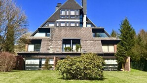 Ein modernes Haus mit einem steilen Dach, großen Fenstern und einem Schornstein.