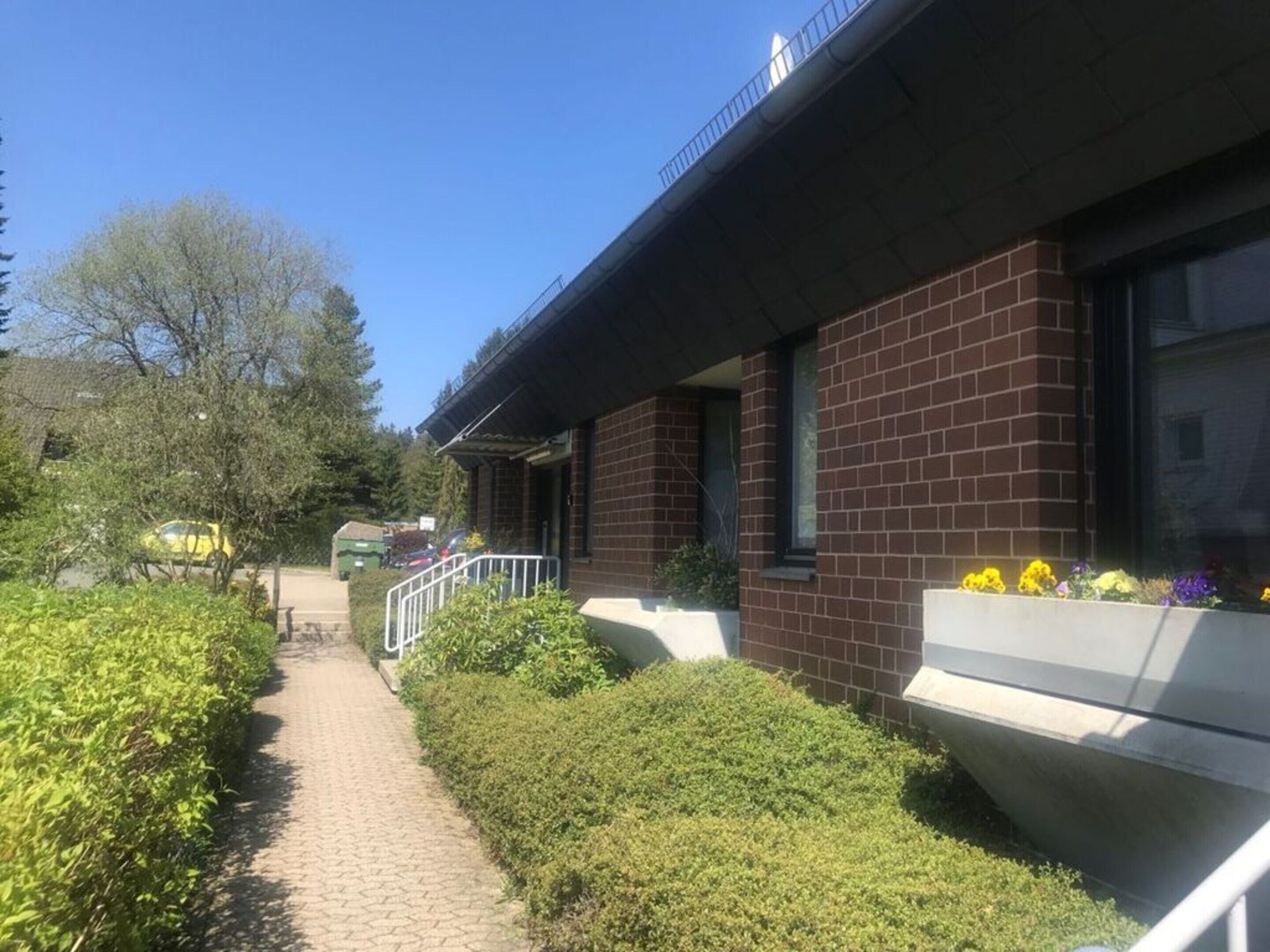 A brick building with a paved pathway and flower boxes.