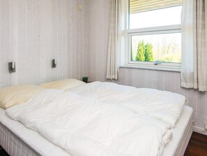 A bedroom with a large bed, a window with curtains, and a small potted plant on the nightstand. - 4 Person Holiday Home in Aabenraa (Aabenraa)