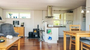 Un salon chaleureux avec une cheminée, des meubles en bois et une cuisine en arrière-plan.