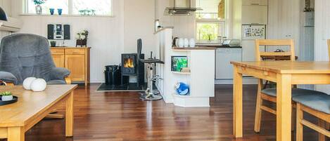 Una sala de estar acogedora con chimenea, muebles de madera y una cocina al fondo.