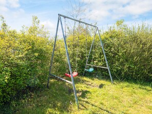 A swing set in a grassy area with dense foliage in the background. - 4 Person Holiday Home in Aabenraa (Aabenraa)