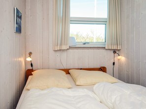 A bed with white bedding and two beige pillows, a window with curtains, and two wall-mounted lamps. - 4 Person Holiday Home in Aabenraa (Aabenraa)