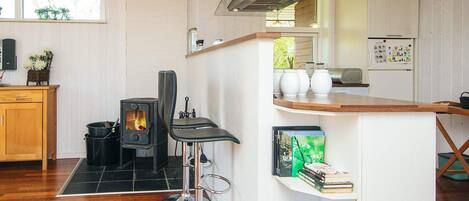Una cocina moderna con estufa de leña, una barra y decoración en tonos blancos.