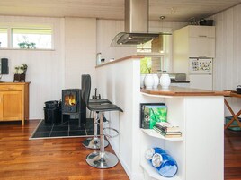 Una cocina moderna con estufa de leña, una barra y decoración en tonos blancos.