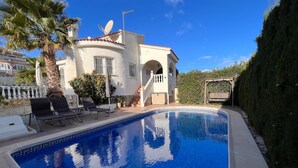 A swimming pool with lounge chairs, a white building with arches, and a well-maintained garden. - Costa Blanca Poolside Bliss (Rojales)
