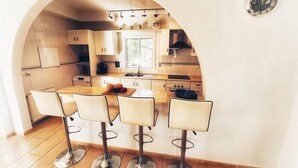 A kitchen with an archway, a dining area with four bar stools, and a wall clock. - Costa Blanca Poolside Bliss (Rojales)