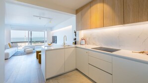 A modern kitchen with white cabinetry, a marble backsplash, and a large island. - Beautiful Apartment With Direct sea View (Middelkerke)