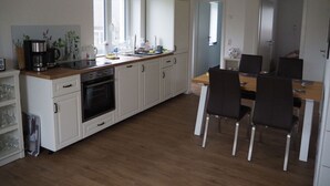 Eine moderne Küche mit weißen Schränken, einer Holzarbeitsplatte und einem Essbereich mit Tisch und Stühlen.