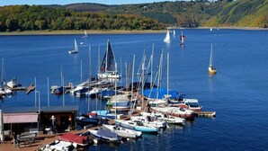 Ein Yachthafen mit vertäuten Booten, ein kleines Gebäude und Hügel im Hintergrund.