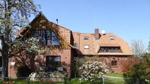 A two-story brick house with a sloped roof, a visible chimney, and a satellite dish.