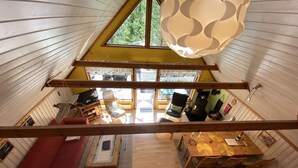 Un ambiente accogliente con un divano rosso, un tavolo da pranzo in legno e un'ampia finestra che offre vista sull'esterno.