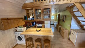 Una cucina compatta con mobili in legno, una lavatrice e un'area pranzo con sgabelli.