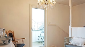 A room with a wooden floor, a white bench, a chair, a table with a pitcher, and a chandelier. - 4 Star Holiday Home in Lysekil (Lysekil)