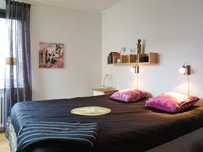 A bedroom with a bed, pillows, a nightstand, a shelf with books and a statue, and a wall-mounted lamp. - 4 Star Holiday Home in Lysekil (Lysekil)