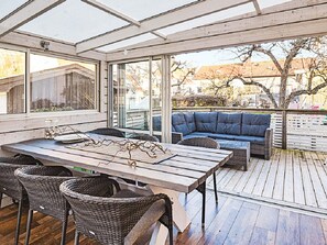 A covered outdoor area with a wooden table, wicker chairs, and a blue sofa. - 4 Star Holiday Home in Lysekil (Lysekil)