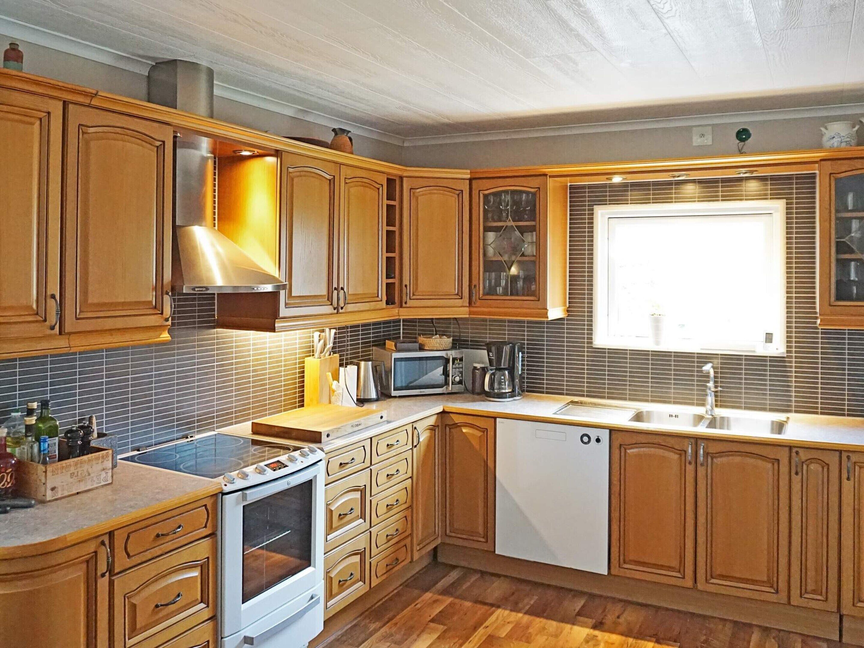 A kitchen with wooden cabinets, a stove, microwave, and a dishwasher.