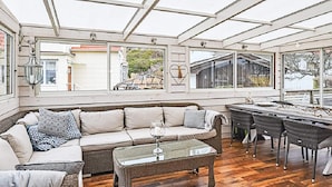 A sunroom with a glass ceiling, a sofa, a coffee table, and a dining area with chairs. - 4 Star Holiday Home in Lysekil (Lysekil)