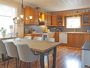 A modern kitchen with wooden cabinets, a dining table with chairs, and a built-in microwave. - 4 Star Holiday Home in Lysekil (Lysekil)