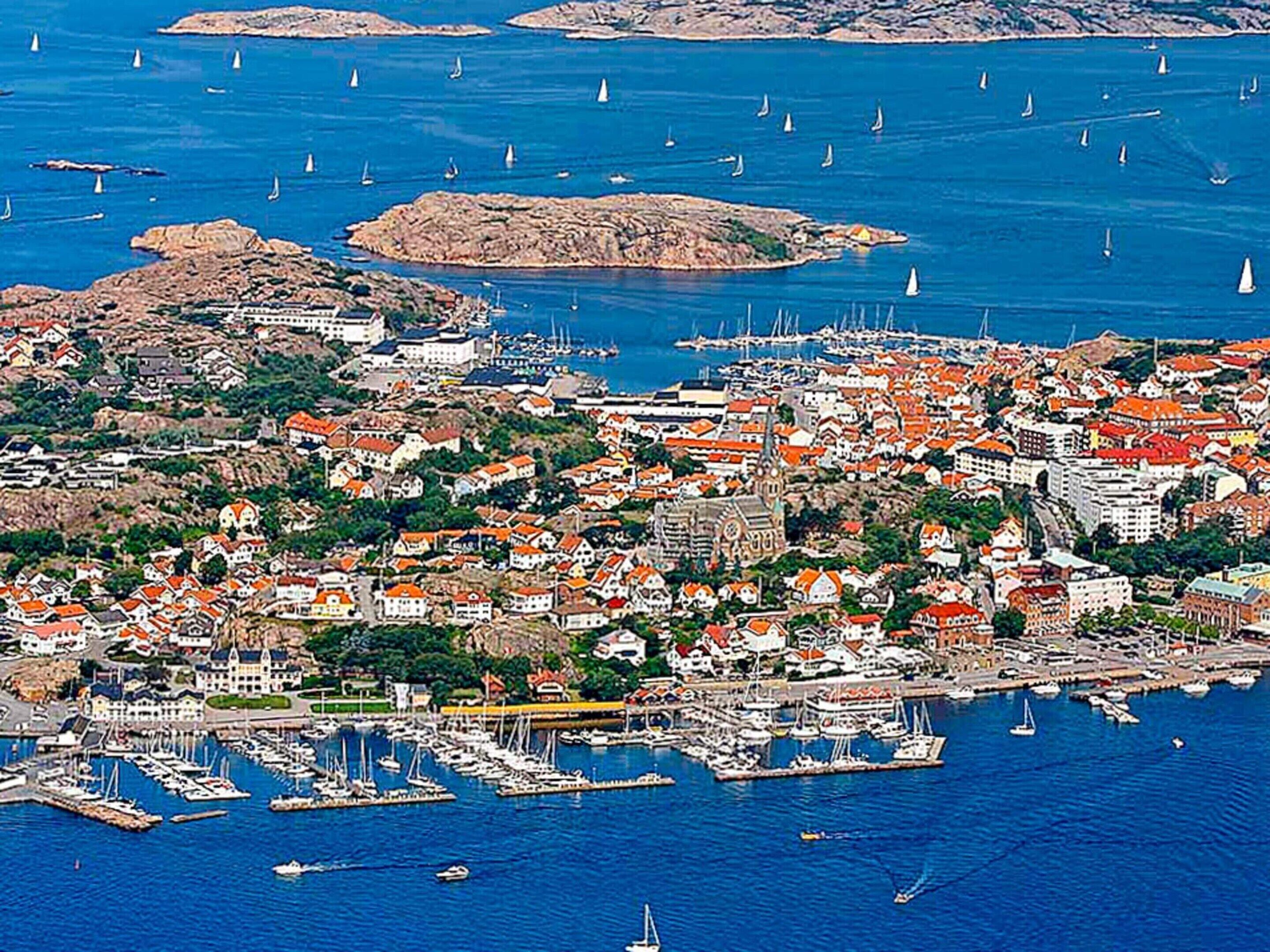 A coastal town with a marina, buildings with red roofs, and sailboats.