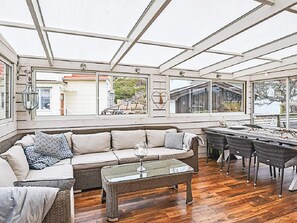 A sunroom with a glass ceiling, a sofa, a dining table with chairs, and a view of the outside. - 4 Star Holiday Home in Lysekil (Lysekil)