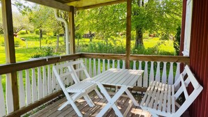 A wooden deck with a table and two chairs, overlooking a green landscape. - 4 Person Holiday Home in Hovmantorp (Hovmantorp)