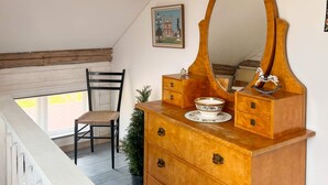 A wooden dresser with a large mirror, a small decorative horse figurine, and a bowl with a floral pattern. - 4 Person Holiday Home in Hovmantorp (Hovmantorp)