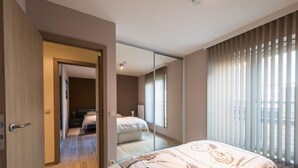 A modern bedroom with a large bed, a walk-in closet, and a view of another room. - Moorea City Center Apartment (Middelkerke)