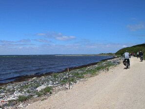 Ein Küstenpfad mit Radfahrern, felsigem Ufer und blauem Himmel.