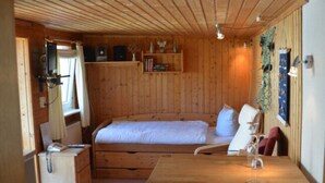 A cozy wooden cabin room with a bed, a desk, and a chair. - Little Beach Flea Comfortable Holiday Residence (Wangerooge)
