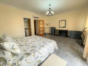 A bedroom with a bed, dresser, mirror, and a chandelier. - Belvilla by OYO Holiday Home in Los Alcazares (Los Alcazares)