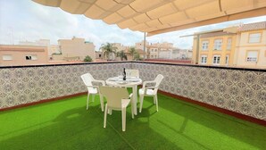 A rooftop terrace with a table and chairs, a patterned wall, and a view of surrounding buildings. - Belvilla by OYO Holiday Home in Los Alcazares (Los Alcazares)