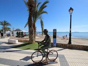 A statue of a man on a bicycle, a palm tree, a beach, and a clear blue sky. - Belvilla by OYO Holiday Home in Los Alcazares (Los Alcazares)