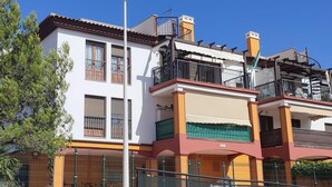 Un immeuble résidentiel à plusieurs étages, doté de balcons, avec un lampadaire et un ciel bleu dégagé.
